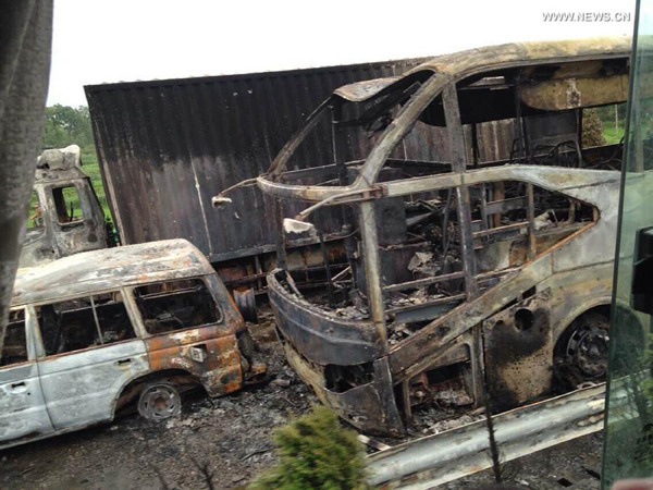 This photo taken by a cellphone on July 19, 2014 shows resucers work at the scene of a vehicle collision on a section of the Hukun Expressway in central China's Hunan Province. The accident happened at around 3 am, when a freight van loaded with flammable liquid rear ended a passenger coach capable of carrying 53 people, according to the provincial traffic police. Four passengers managed to escape with major burns, while the conditions of the rest remain unclear. (Xinhua)