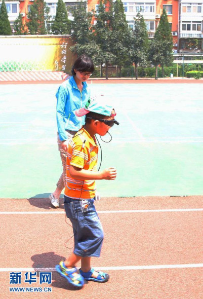Binbin wears a magnetic electronic device to practice walking under the guidance of a nurse in Beijing on July 15, 2014. [Photo: Xinhua]