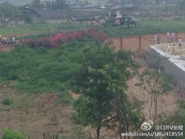 Villagers climbed walls to get a good view of the crashed helicopter, photo taken on Monday evening, July 21, 2014. [Photo: theBeijingnews] 