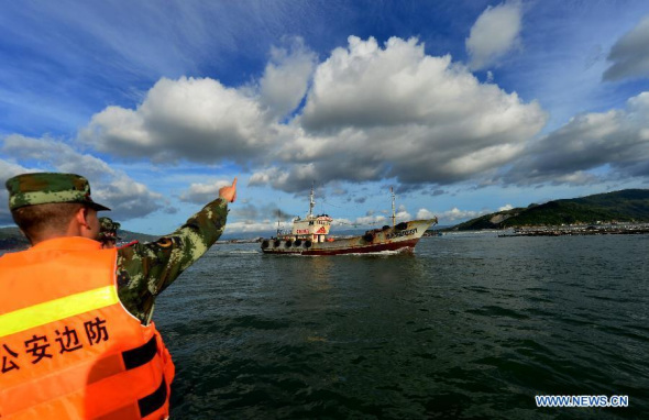 A soldier guides a fishing boat at Luoyuan dock in Fuzhou, southeast China's Fujian Province, July 22, 2014.  (Xinhua/Wei Peiquan) 
