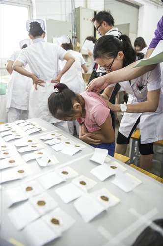 A young girl has a sanfu patch applied to her exposed back. Sanfu patch therapy is a traditional Chinese medicinal remedy administered in the summer to mitigate the effects of illnesses common in the winter. Photo: Li Hao/GT