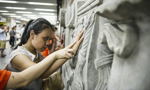 Blind woman Niu Liyun touches a sculpture with the aid of volunteers. Photo: Li Hao/GT