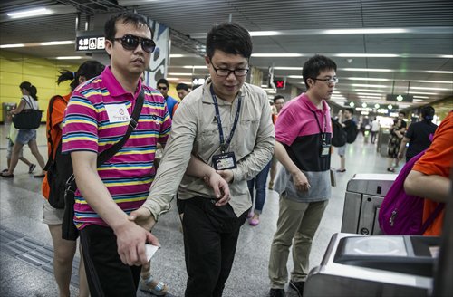 Volunteers help blind people buy tickets and enter the subway. Photo: Li Hao/GT