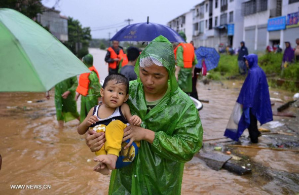 A rescuer helps a little boy transfer to safety place in Baota Township of De'an County, east China's Jiangxi Province, July 24, 2014.  (Xinhua/Zhou Mi)