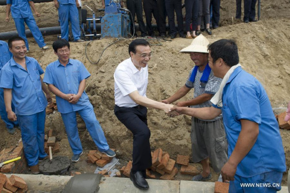 Chinese Premier Li Keqiang (C front) shakes hands with a worker on a rain sewage diversion system construction site in Lingxian County of Dezhou, east China's Shandong Province, July 24, 2014. Li had an inspection tour in Shandong from July 24 to 25. (Xinhua/Huang Jingwen)