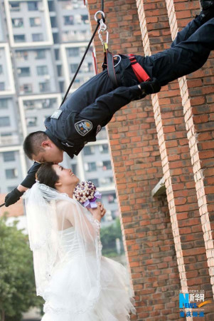 A SWAT officer named Hou Weilin rappels down a tall building and kisses the forehead of his fiancee, who is wearing her wedding dress. The official Weibo account of Chongqing special police corp released a series of unique engagement photos on July 25, 2014, which went viral online. [Photo: Xinhua]