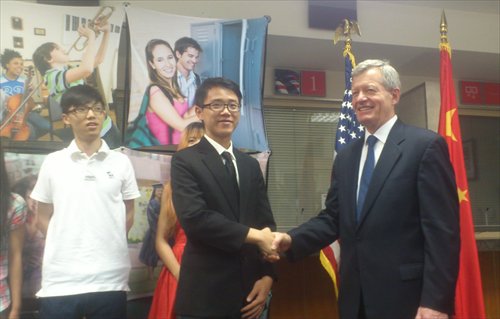 US ambassador to China Max Baucus shakes hands with a Chinese student who just received his student visa to the US. 