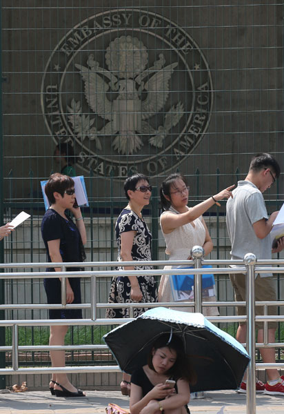 People wait outside the United States embassy in Beijing on Monday for visa applications. A computer problem that occurred in the US visa application system on July 19 has significantly reduced the embassy's capacity for handling visa applications. Wang Jing / China Daily