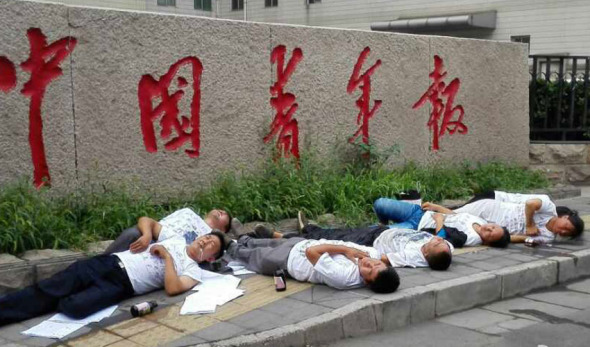 Seven petitioners lying on the ground, with bottles suspected to contain pesticide. Photo taken on the morning of July 16, 2014. [Photo: China Youth Daily]