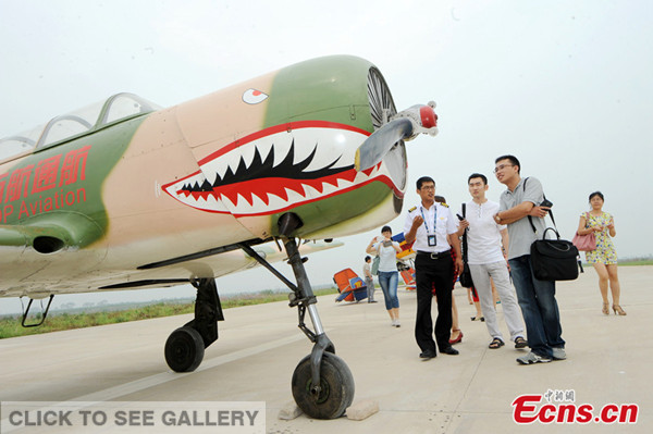 Visitors look at a plane at Tianjin's first private flying club opened on July 13, 2014 at an airport of the city. [Photo: China News Service/ Tong Yu]
