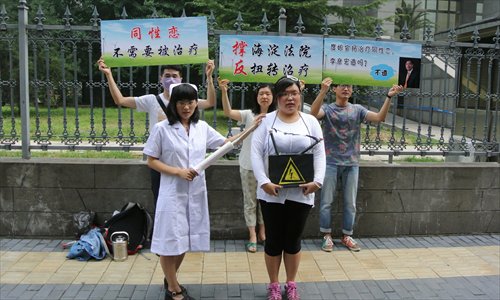 LGBT rights campaigners hold placards with slogans such as Homosexuals don't need treatment outside the Haidian court in Beijing on Thursday. Photo: Li Hao/GT