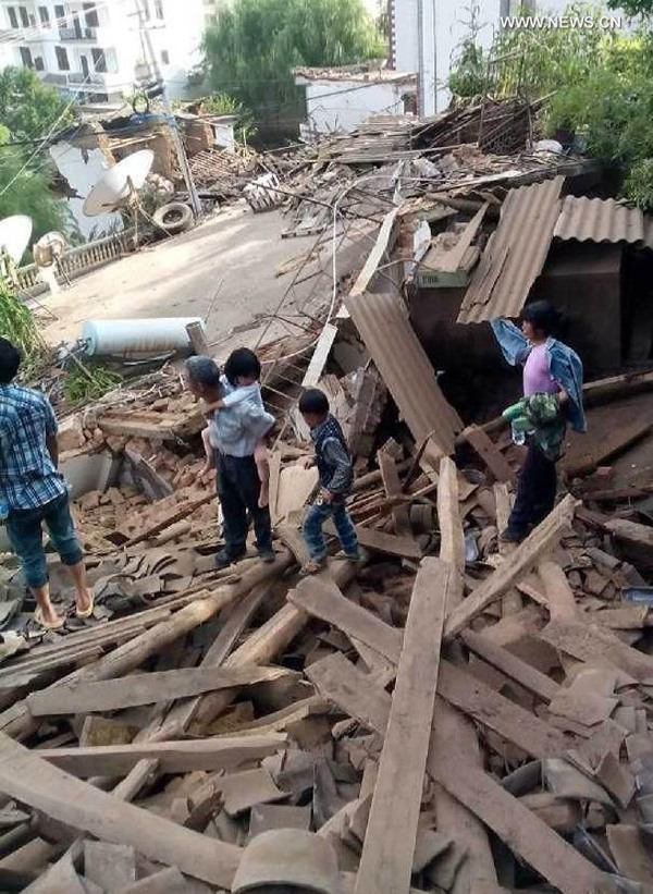 This photo taken by cellphone on Aug. 3, 2014 shows people standing on a damaged house after an earthquake in Ludian County of Zhaotong City in southwest China's Yunnan Province. A 6.5-magnitude earthquake jolted Ludian County at 4:30 p.m. Sunday (Beijing Time), said the China Earthquake Networks Center (CENC). (Xinhua)