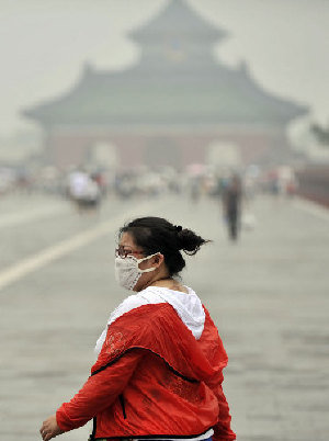 A mask-wearing woman walks in the Temple of Heaven during an extremely smoggy day in Beijing in July. Li Wen / Xinhua