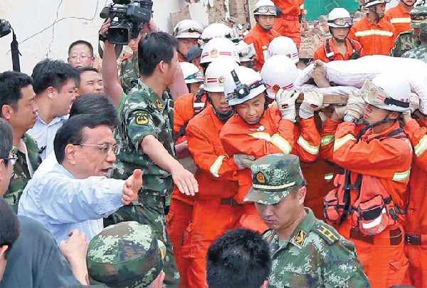 Premier Li Keqiang helps make way for rescuers carrying victims on Monday while inspecting the township of Longtoushan, epicenter of Sunday's earthquake in Yunnan province. Yao Dawei / Xinhua