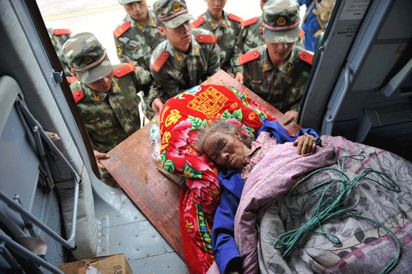 People's Liberation Army soldiers transfer an injured elderly person at Longtoushan township in Ludian county of Yunnan province on Monday. The magnitude-6.5 earthquake has so far left at least 398 people dead, three people missing and another 1,801 people injured. [Photo/Xinhua]