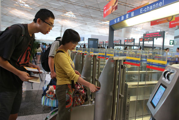 Passengers pass through customs via e-channel where they can swipe passports and have faces scanned by the new facial identification equipment at Beijing Capital International Airport on July 25. Wang Jing / China Daily