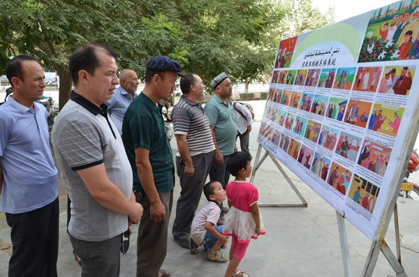 Local villagers in Shache county examine illustrations teaching them how to identify extreme religious acts on Tuesday in Kashgar prefecture, in the Xinjiang Uygur autonomous region. Chen Jing / for China Daily
