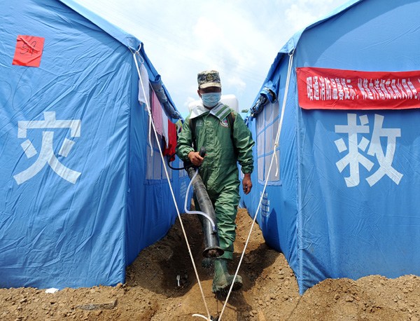 A soldier disinfects a tent camp in Ludian county, Yunnan province, on Thursday. Chen Liang / for China Daily
