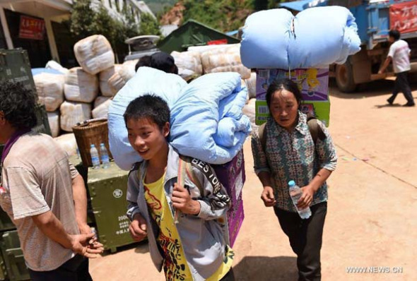 Victims in Ludian earthquake get cotton quilts and instant noodles in quake-hit Longtoushan Town of Ludian County, southwest China's Yunnan Province, Aug. 8, 2014. 44510 tents, 10000 emergency lights, 65997 overcoats have arrived in the quake stricken area. 11 villages of Longtoushan Town have already received relief materials. (Xinhua/Lin Yiguang)