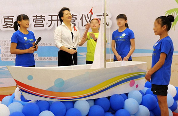 Peng Liyuan, China's first lady and a World Health Organization ambassador in the fight against HIV/AIDS, helps raise a white sail at the opening ceremony of a summer camp for AIDS orphans in Beidaihe, Hebei province, on Friday. Provided to China Daily