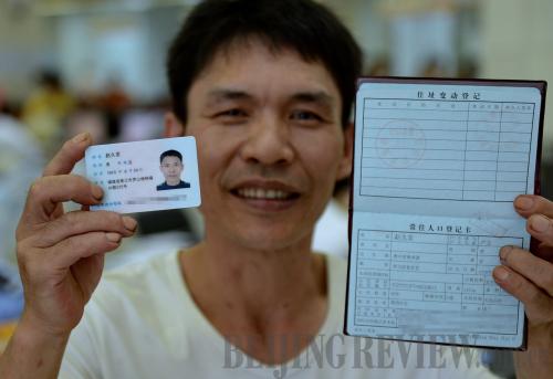 NEW IDENTITY: Zhao Jiufa, a migrant worker from southwest China's Guizhou Province, displays his new hukou and ID card in Jinjiang, Fujian province, in the southeast part of the country, on June 26 (ZHANG GUOJUN)