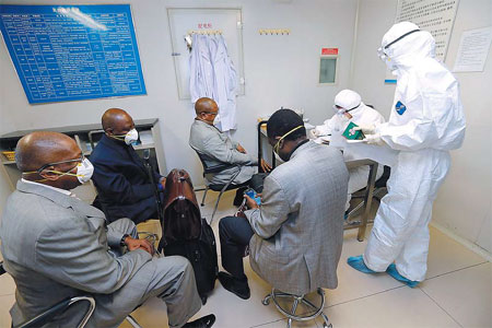 Quarantine officers with the entry-exit inspection and quarantine bureau at the Beijing Capital International Airport give body temperature tests to four passengers from Nigeria on Thursday. They all passed the test and were allowed through the border. Shen Bohan / Xinhua