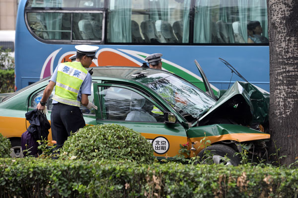 Police officers inspect a taxi on Sunday morning in Beijing after it crashed into a tree along the Third Ring Road at about 6 am, causing the deaths of the driver and two passengers. Zhao Siheng / for China Daily