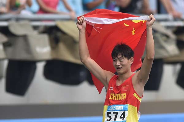 Gold Medalist Xu Zhihang of China holding the national flag of China, celebrates after the Men's 400m Hurdles Final of athletics event at the Nanjing 2014 Youth Olympic Games in Nanjing, the capital of East China's Jiangsu province, Aug 25, 2014. [Photo/nanjing2014.org]