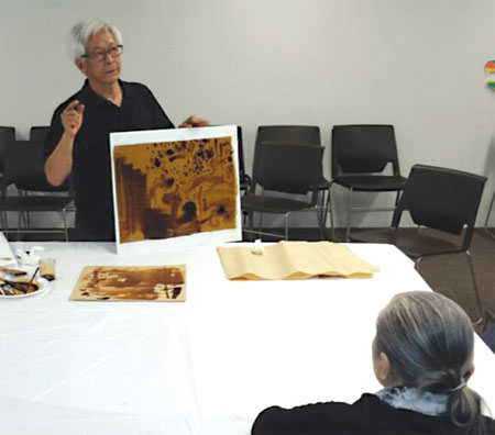 Zhang Hongtu (standing) displays some of his techniques for painting using soy sauce on Saturday at an event hosted by the Museum of Chinese in America in New York on Aug 23. Jack Freifelder / China Daily