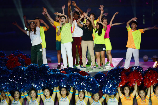 Canadian singer Carlo Aspri (center left) performs with youth athletes at the Nanjing Olympic Sports Center Stadium during the closing ceremony of 2014 Youth Olympic Games in Nanjing, Jiangsu province, on Thursday. [Photo by Wei Xiaohao/China Daily]
