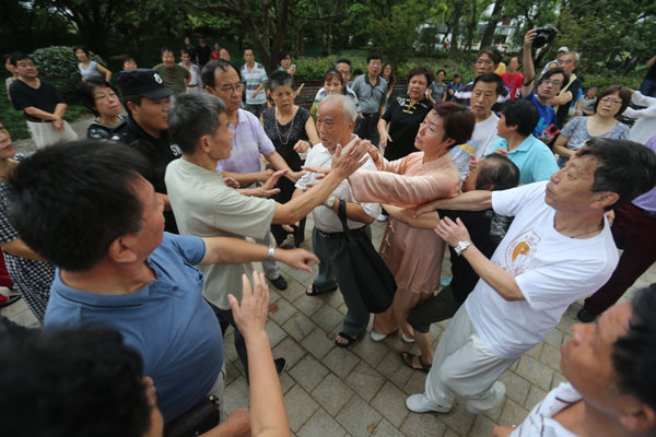 A group of tai chi enthusiasts and a group of ballroom dancing amateurs get into a dispute over who gets to use an area inside Luxun Park in Shanghai on Thursday morning. Liu Xin / for China Daily