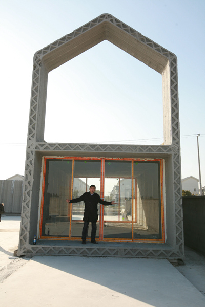A man stands inside a house in Shanghai that was constructed with materials made by 3-D printing technology. Gao Erqiang / China Daily