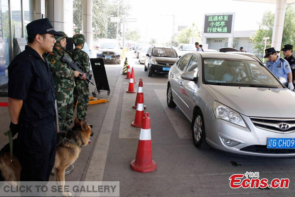 Armed guards and police dog are at a border checkpoint of Beijing on August 12, 2014. [Photo: China News Service / Ren Haixia] 