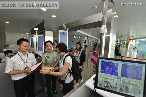 Customs and quarantine staff members hand out brochures about preventing Ebola virus disease to passengers arriving at Lukou International Airport in Nanjing, capital of east China's Jiangsu Province, Aug. 12, 2014. (Xinhua/Xie Mingming)