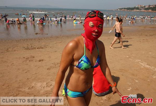 A woman wearing "facekini" joins an activity marking the National Fitness Day at a bathing beach in Qingdao, Shandong province on August 8, 2014. [Photo: China News Service/ Xu Chongde]