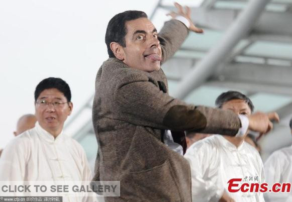Rowan Atkinson, well known as Mr. Bean, a British comedian, makes faces while joining in a group dancing with old people on a square in Shanghai on August 20, 2014. Photo/CFP