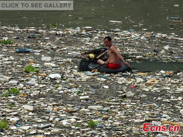 A boat is encircled by floating wastes in the Three Gorges Reservoir in Zigui county, Central China's Hubei province on August 24, 2014. [Photo: China News Service/ Liu Junfeng]