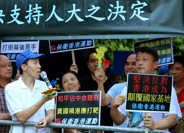 Hong Kong citizens hold banners outside the government's office in support of a decision by the National People's Congress Standing Committee on Sunday to grant universal suffrage in the selection of the special administrative region's chief executive on the basis of nomination by a broadly representative committee. [Photo by Edmond Tang / China Daily]