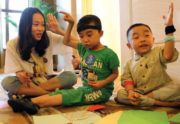 A volunteer playing with children suffering from osteogenesis imperfecta at an event organized by the Beijing-based China-Dolls Center for Rare Disorders. ZHU XINGXIN / CHINA DAILY
