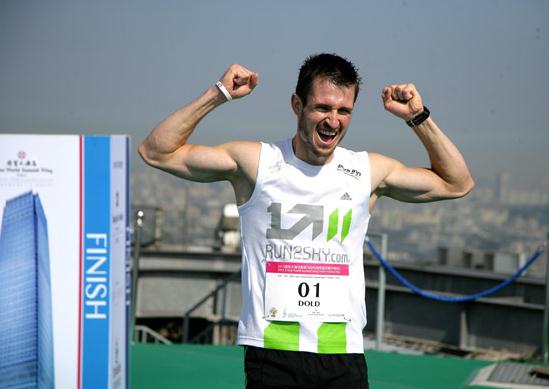 German Thomas Dold celebrates being the first man to finish the vertical marathon at the rooftop of World Trade Center Tower 3 in Beijing on August 3, 2013.[Photo provided to chinadaily.com.cn]