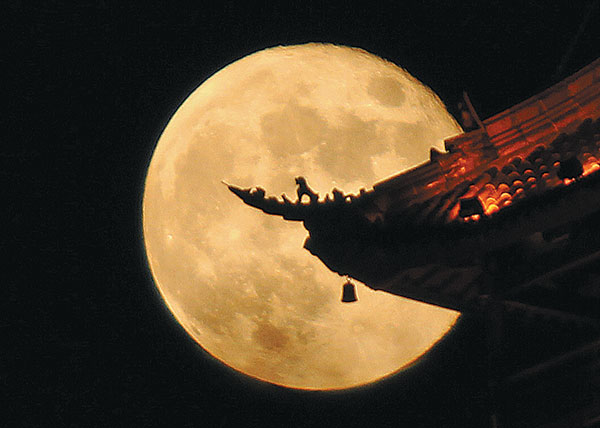 An animal sculpture on the eaves of a building is silhouetted against a full moon at the Wolf Mountain Scenic Area in Nantong, Jiangsu province. XU CONGJUN/CHINA DAILY