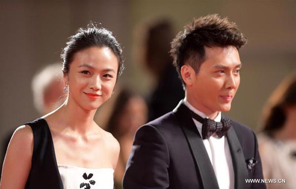Actress Tang Wei (L) and actor Feng Shaofeng pose on the red carpet for the awards ceremony at the 71st Venice Film Festival, in Lido of Venice, Italy on Sept 6, 2014. The Golden Era directed by Ann Hui was screened as the closing film for the festival.[Photo/Xinhua]  