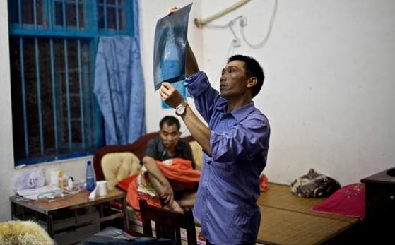 Xu Xinsheng, a patient of pneumoconiosis in Leiyang of Hunan province, examines lung scans of Xu Zhihui, another sufferer of the disease, on Aug 23, 2013. PHOTO BY ZHOU GANGFENG / FOR CHINA DAILY  