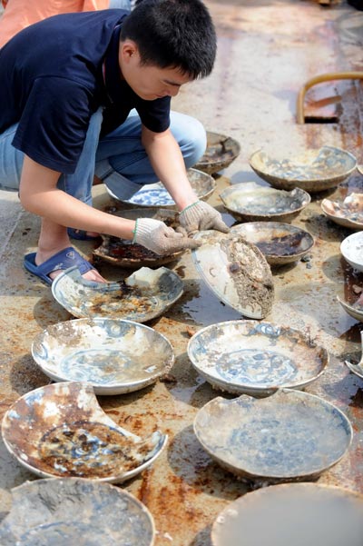 An archeologist cleans items of porcelain from Nan'ao One. [Photo/Xinhua]  