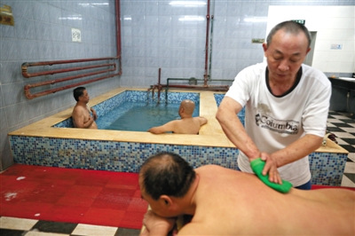 The photo above shows a customer and a staff member in the century-old Xinyuan Bathhouse in Beijing. [Photo: The Beijing News]