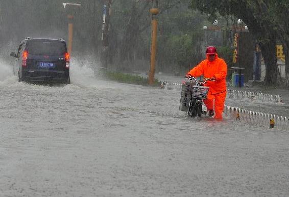A sanitary worker wades through water on the street in Haikou, Hainan province after typhoon Kalmaegi landed in Wenchang city of the island province at 9:40 am on Tuesday. [Photo/Xinhua]  
