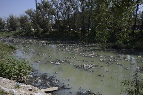 Garbage is seen floating down a polluted waterway near Dong Xindian village in Beijing's Chaoyang district on September 9, 2014. [Photo: the beijingnews]