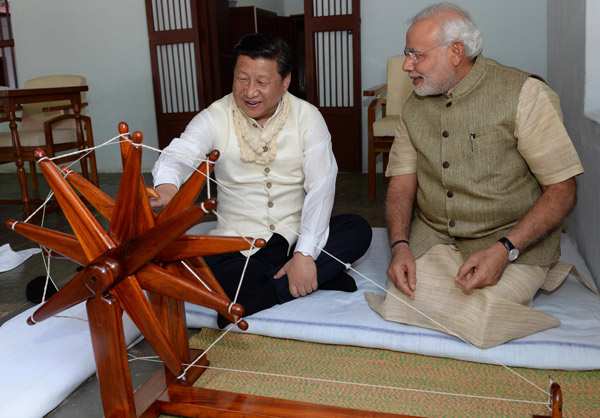 Accompanied by Indian Prime Minister Narendra Modi, President Xi Jinping moves a spinning wheel once used by Mohandas Gandhi, in a memorial paying homage to India's independence leader in Gujarat, India, on Wednesday. [Photo/Xinhua]