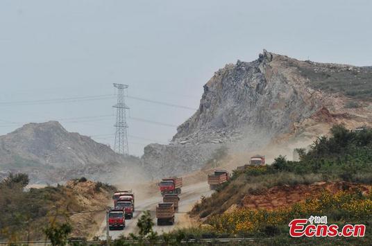 Heavy duty trucks are used to transport earth and stones removed from mountain to construction site of an offshore airport in Dalian, Northeast Chinas Liaoning province on September 14, 2014. [Photo: China News Service/ Liu Debin]