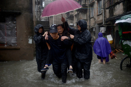 Community officials evacuate residents in an old residential area in Taizhou, Zhejiang Province, yesterday before typhoon Fung-Wong made landfall in the eastern provinces Xiangshan County. More than 250,500 people were forced to flee their homes across the province by midday.  Xinhua